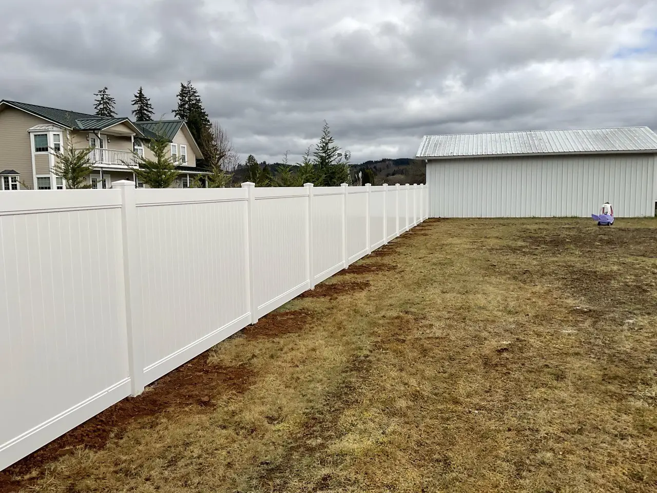 Long run of white vinyl privacy fence along a residential property line